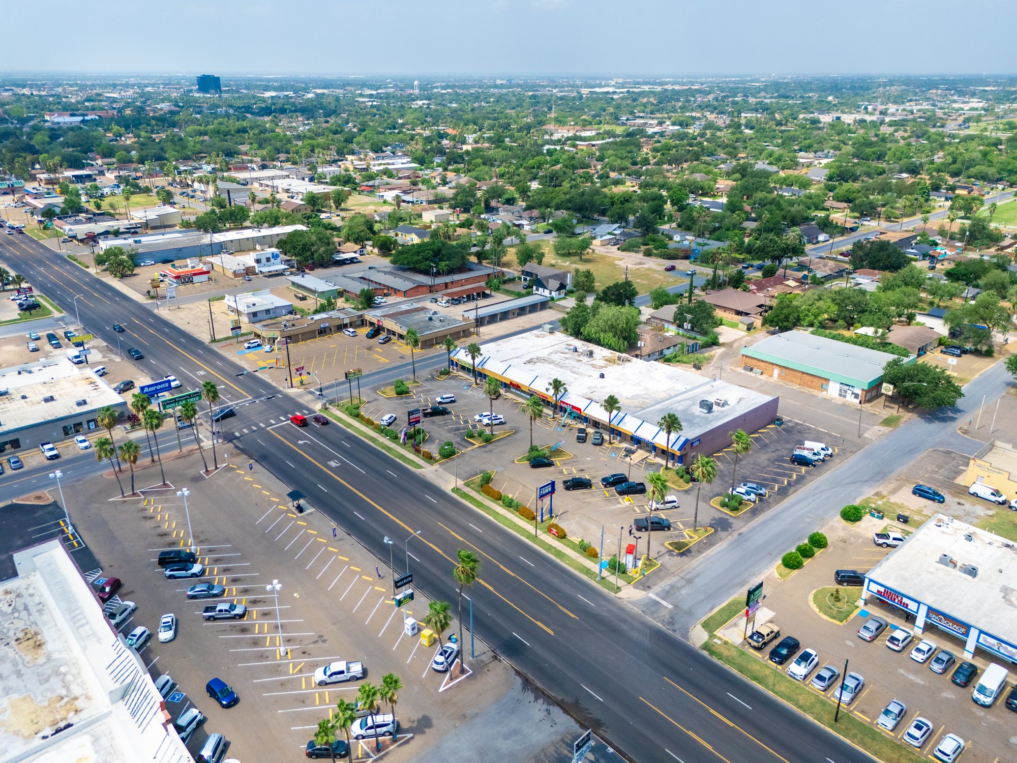 Aerial view of a multi-tenant retail center in McAllen, Texas, with individual storefronts, a shared parking lot and frontage on a major arterial road